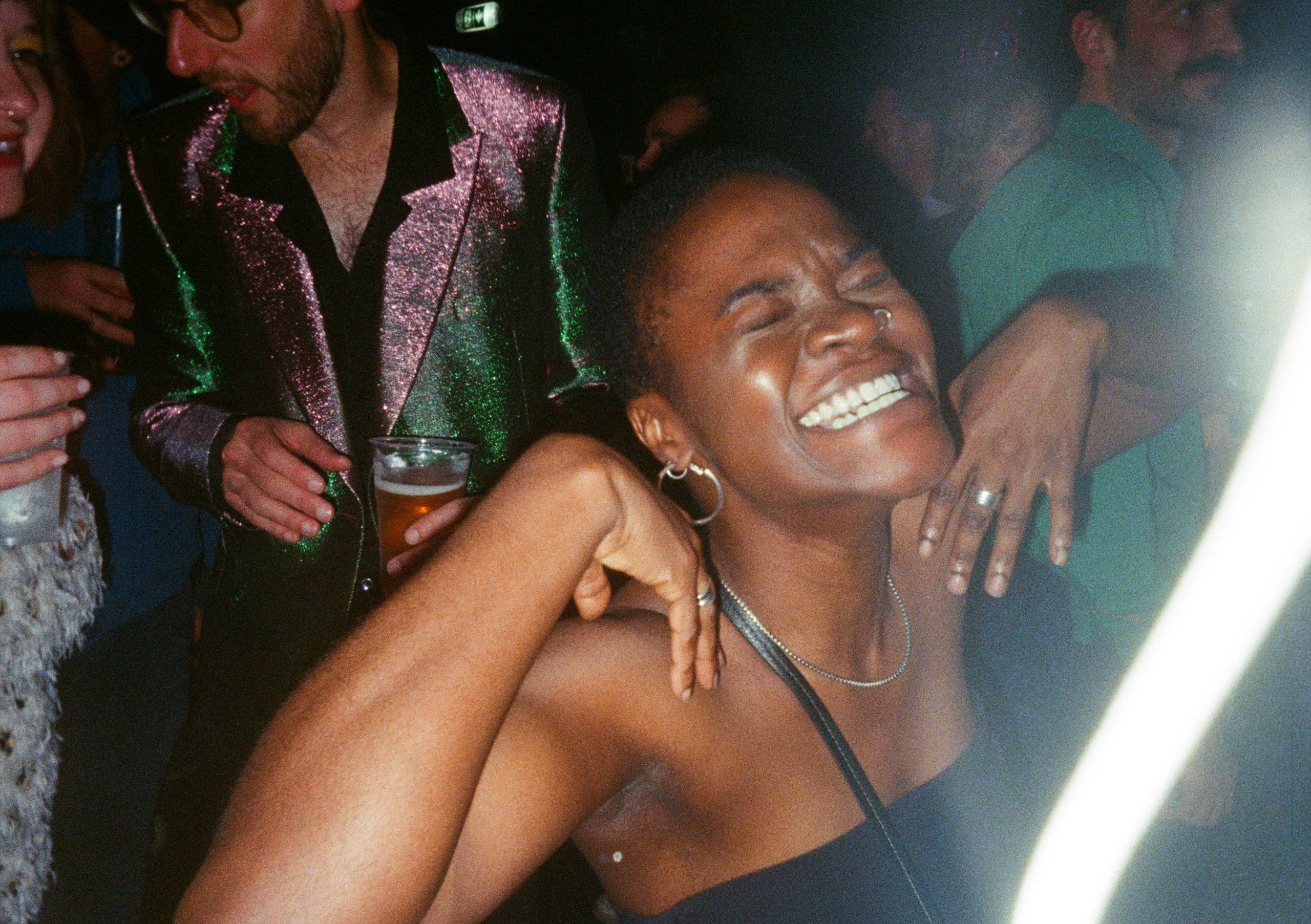 Film photo of a guest laughing with her eyes shut on a packed dance floor
