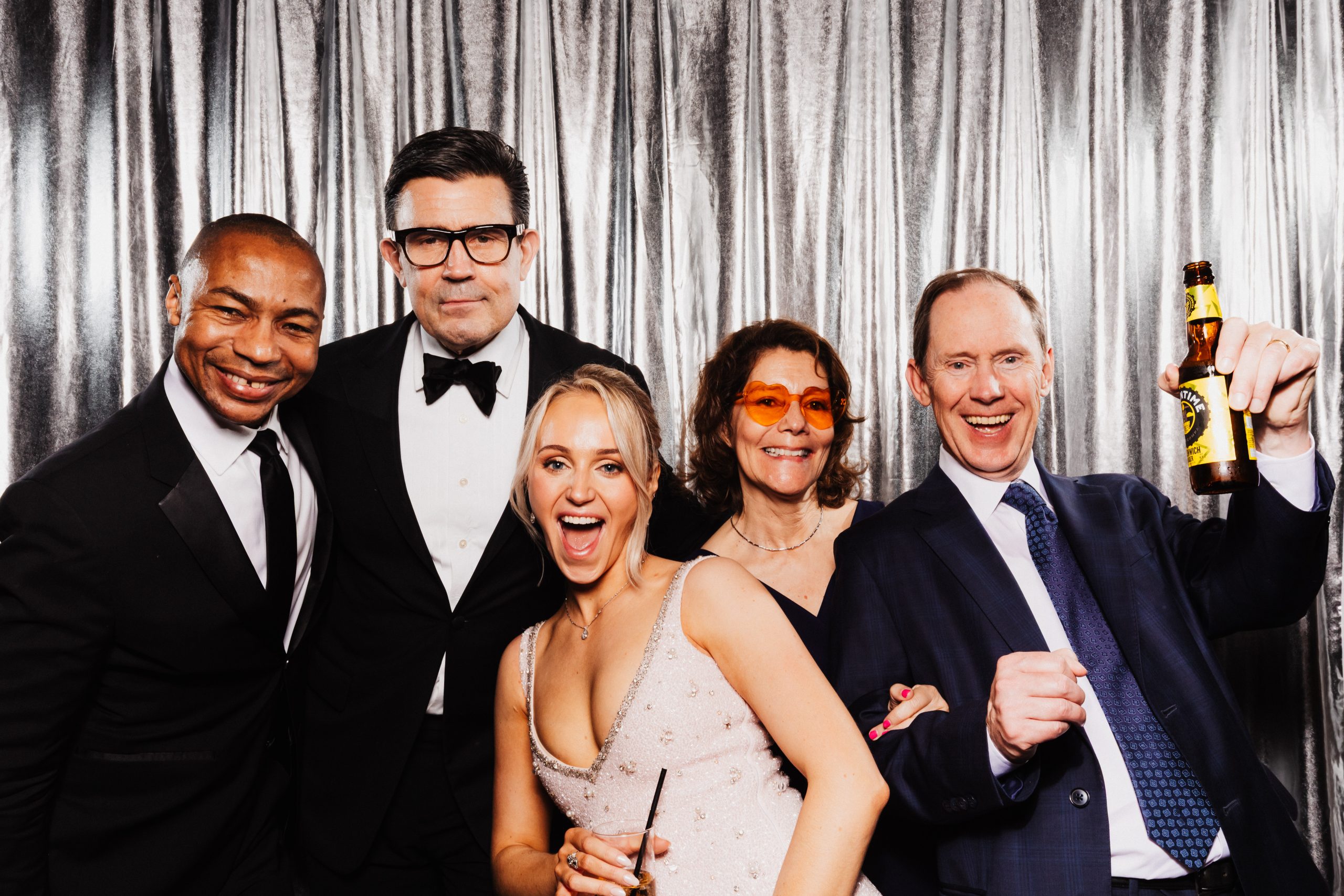 Booth print of a group of wedding guests in suits and dresses, some in sunglasses, posing together