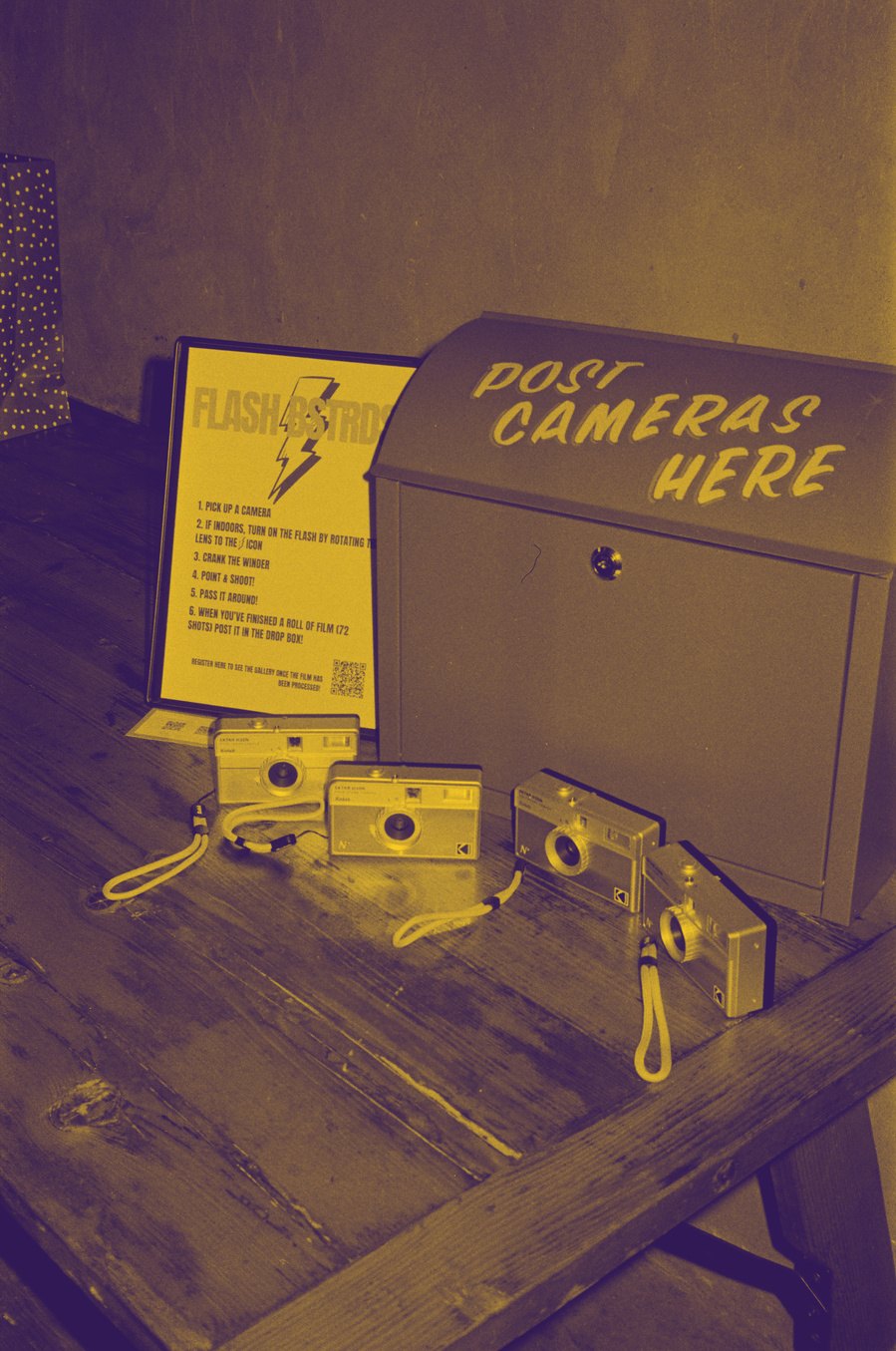 Film Fiends point and shoot cameras laid out next to the POST CAMERAS HERE drop box and instruction sheet